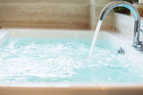 Lussuosa vasca idromassaggio che si riempie di acqua turchese all'hotel Bluemoon Sardinia di Cagliari