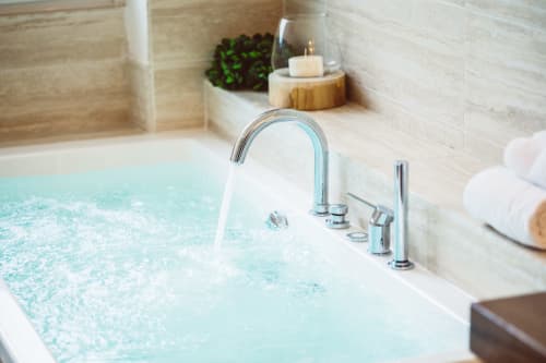 Vasca idromassaggio di lusso che si riempie di acqua turchese presso la suite Bluemoon Sardinia a Cagliari