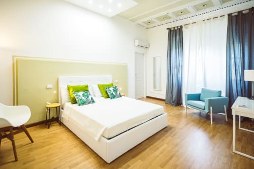 Modern Double King Room at Bluemoon Sardinia in Cagliari with yellow accent wall, green pillows, teal chair, and wooden