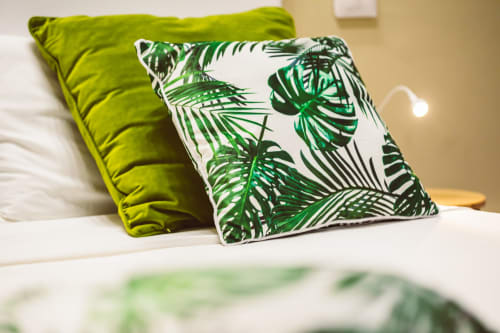 Lime green and tropical leaf-patterned pillows on a bed in Bluemoon Sardinia's Double King Room, Cagliari