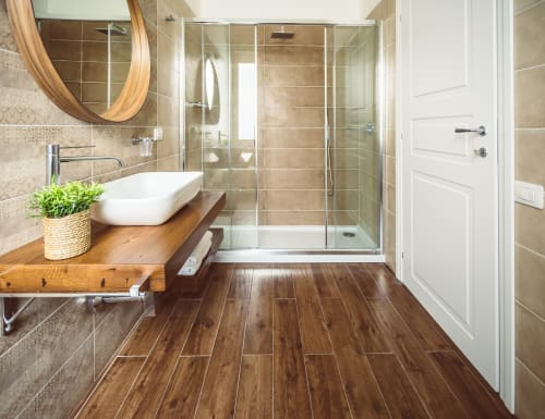 Modern bathroom at Bluemoon Sardinia, Cagliari with wooden vanity, vessel sink, glass shower enclosure, and wood-look