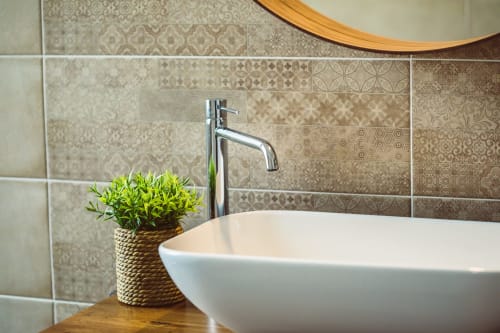 Modern bathroom vanity at Bluemoon Sardinia with white vessel sink, chrome faucet, and patterned tile backsplash in Cagliari