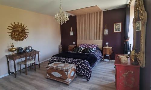 Suite élégante aux Forges Du Lou avec murs d'accent sombres, lustre, parure de lit motifs et mobilier d'époque