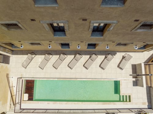 Vista aérea del área de piscina del Hotel La Prison en Béziers con tumbonas y agua verde