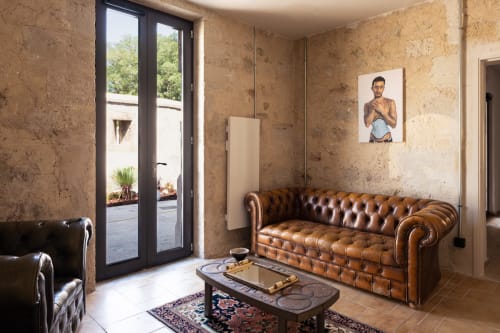 Lujoso salón del Hotel La Prison en Béziers con sofás Chesterfield de cuero marrón, paredes de corcho y acceso a la terraza