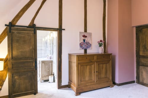 Chambre rustique au Prieuré Du Preux avec poutres apparentes, mobilier en bois, murs roses et portes de grange à Sépeaux Saint