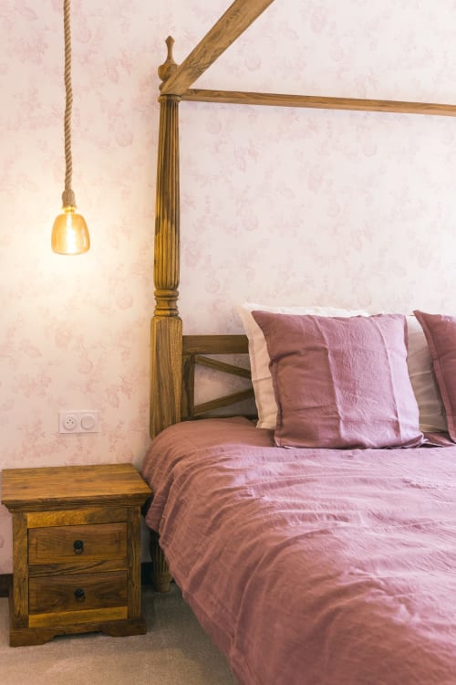 Lit à quatre colonnes en bois avec draps et oreillers roses au Prieuré Du Preux, lampe suspendue au-dessus de la table de nuit en bois