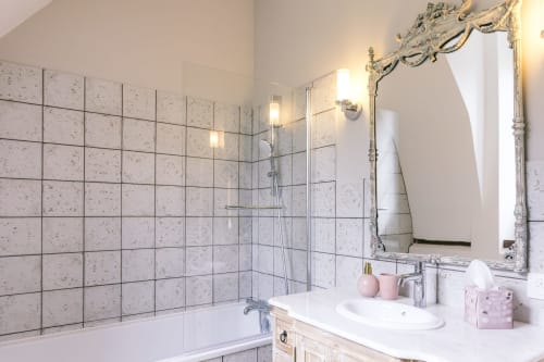 Salle de bain élégante de la chambre Les Clos au Le Prieuré Du Preux avec carrelage en marbre, douche vitrée, miroir orné et vasque blanche