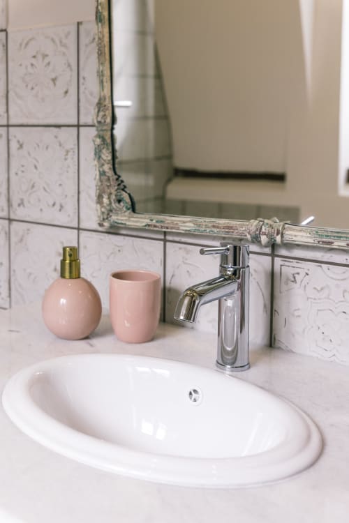 Lavabo moderne avec robinetterie chromée, accessoires roses et miroir décoratif au Prieuré Du Preux B&B