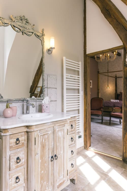 Salle de bain rustique de la chambre Les Clos au Le Prieuré Du Preux, avec vasque blanchie à la chaux, poutres en bois et accès à la vue sur le jardin