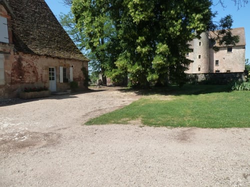 Edificios históricos de piedra y árbol cubierto de hiedra en el Château De Clusors, casa rural francesa en Saint-Menoux