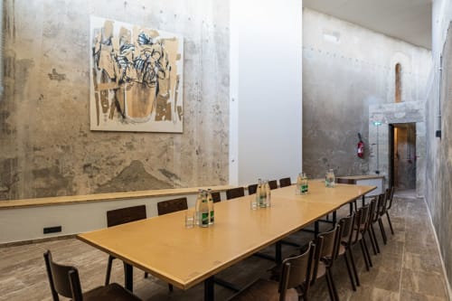 Salle de réunion moderne à l'Hôtel La Prison à Béziers avec table en bois, chaises noires et art mural contemporain.