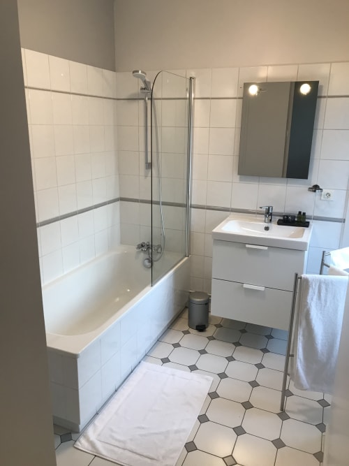 Salle de bain moderne à Chablis Appart avec murs en carrelage blanc, douche vitrée, lavabo et carrelage hexagonal
