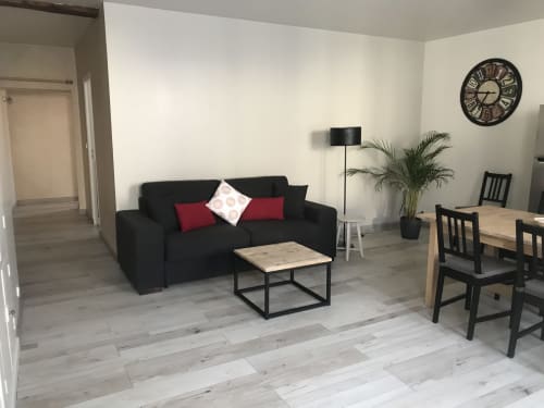 Séjour contemporain aux Appartements Chablis avec canapé noir, table en bois et espace repas à Chablis, France