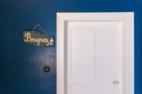 Entrée de la chambre Bougros au Prieuré du Preux avec murs bleus, porte blanche et panneau décoratif