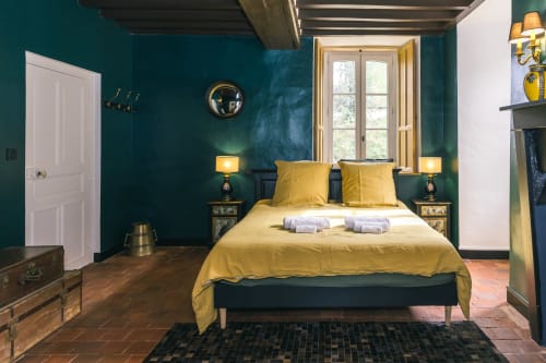 Chambre Bougros au Prieuré du Preux avec murs bleu-vert, literie jaune, fenêtres sur le jardin et décor rustique.
