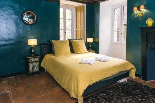 Chambre luxueuse du Prieuré Du Preux aux murs bleu canard, literie jaune et accents dorés, surplombant le jardin des Sépeaux
