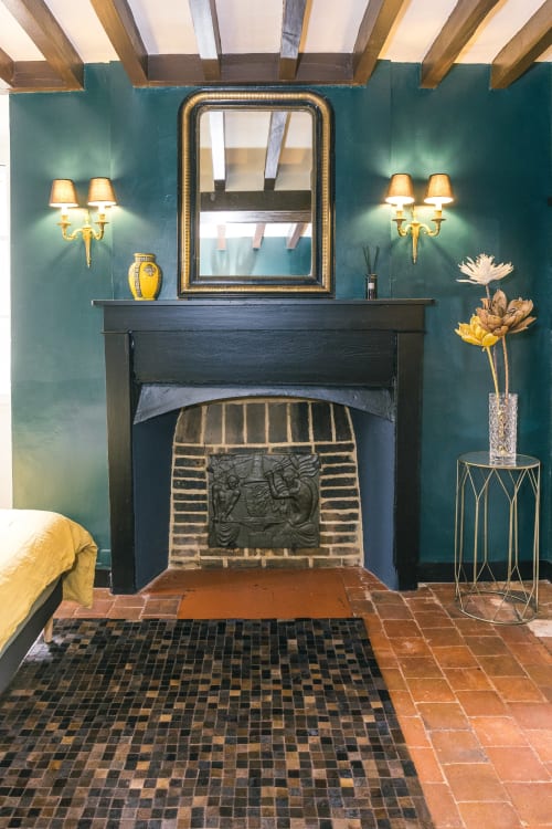 Elegant fireplace with teal walls, gold sconces, and wooden beams in Bougros room at Le Prieuré Du Preux