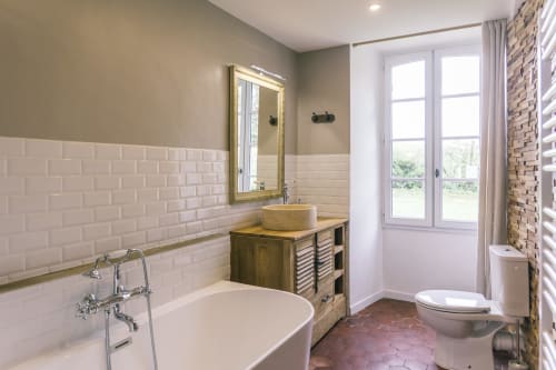Salle de bain moderne au Prieuré Du Preux avec baignoire îlot, meuble en bois, carrelage blanc, vue et accès au jardin