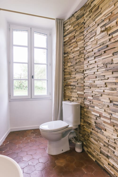 Salle de bain moderne au Prieuré Du Preux avec mur en bois, toilettes et fenêtre donnant sur le jardin