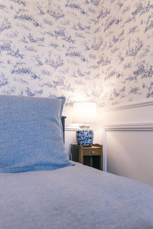 Chambre Blanchot au Prieuré Du Preux avec papier peint toile bleu, lit avec oreiller bleu, table de nuit en bois et lampe en céramique