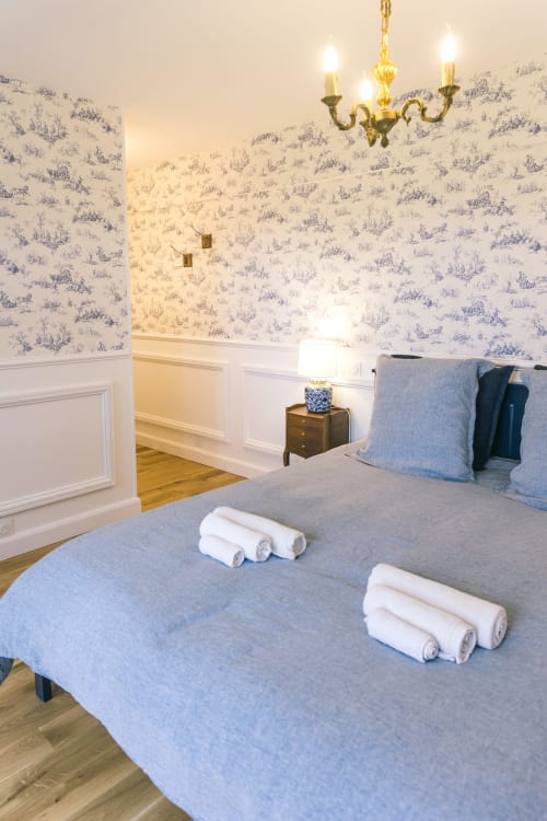 Chambre élégante au Le Prieuré Du Preux avec papier peint toile bleu, lustre en laiton et serviettes roulées sur le lit