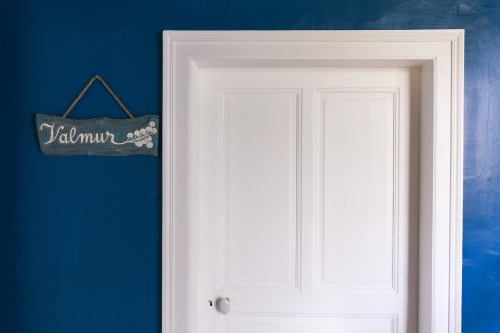 Valmur room door at Le Prieuré Du Preux with blue wall and wooden nameplate sign