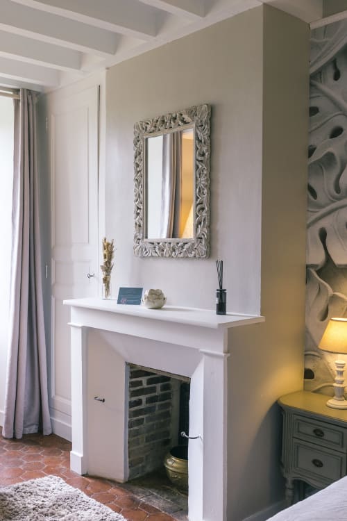Elegant fireplace mantel with decorative mirror in Valmur room at Le Prieuré Du Preux boutique hotel, France