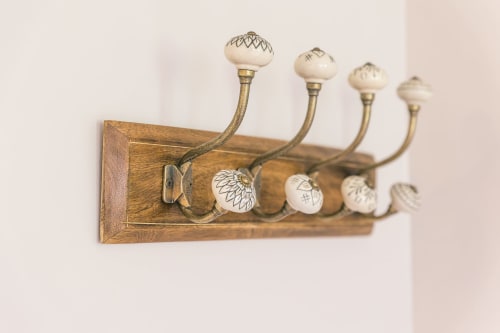 Vintage wooden wall-mounted coat rack with brass hooks and ceramic knobs in Valmur room at Le Prieuré Du Preux, France