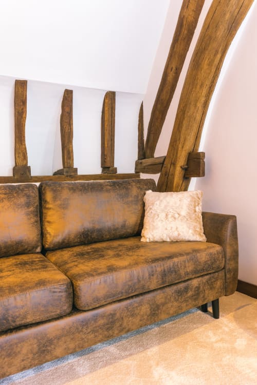 Canapé en cuir rustique avec coussin crème sous les poutres apparentes de la Chambre VAUDESIR au Prieuré Du Preux