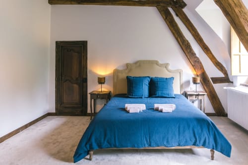 Chambre douillette du Prieuré Du Preux avec literie bleue, poutres apparentes et vue sur le jardin à Sépeaux