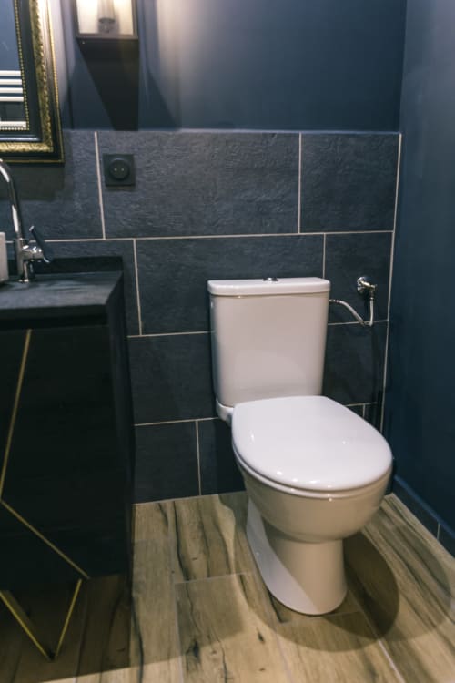 Toilettes modernes avec abattant blanc dans une salle de bains carrelée sombre au Prieuré Du Preux, Sépeaux Saint Romain