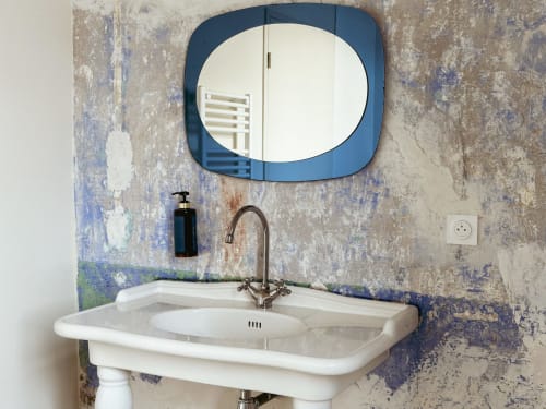 Lavabo del baño del Hotel La Prison con espejo de marco azul en pared azul envejecida y crema en Béziers