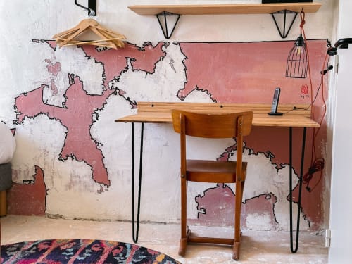 Área de trabajo en el Hotel La Prison Béziers con escritorio de madera, silla y mural de mapa de fondo