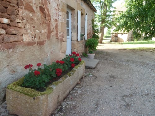 Geranios rojos en jardinera de piedra a la entrada del cottage, Château De Clusors, Saint-Menoux