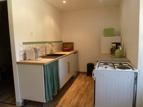 Pequeña cocina en la casita Château De Clusors con fregadero, estufa, electrodomésticos blancos y detalles en verde