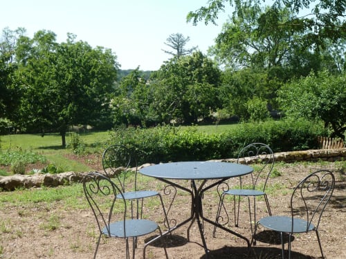 Elegante mobiliario de jardín de metal con vistas a los exuberantes jardines del Château De Clusors B&B en ST MENOUX