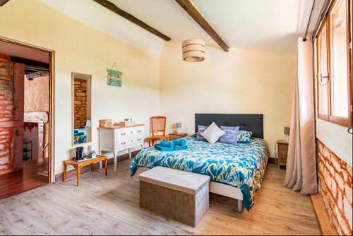 Helles Schlafzimmer im La Maison de la Colline B&B in Vers mit blauem Musterbettzeug, Holzbalken und rustikalen Möbeln