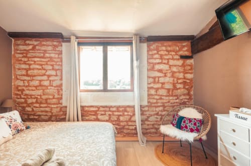 Gemütliches Schlafzimmer im La Maison de la Colline B&B in Vers, Frankreich, mit Backsteinmauern und Fensterblick