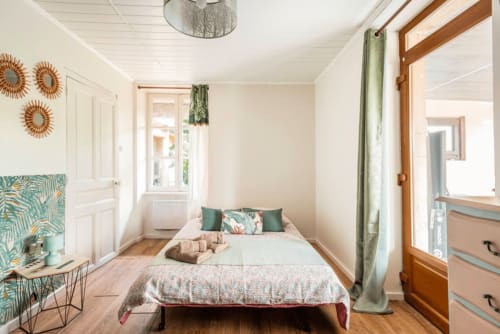 Helles Schlafzimmer in der Pension La Maison de la Colline B&B in Vers, Frankreich, mit Bett, Gartenfenstern, Holzmöbeln und Grünflächen