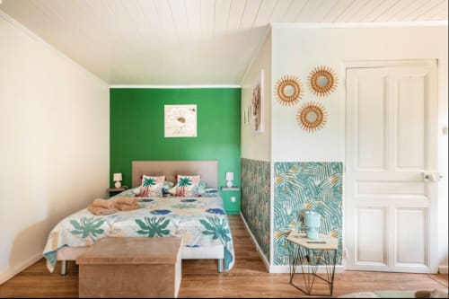 Helles Schlafzimmer mit grüner Akzentwand, tropischer Bettwäsche und Gartenblick in La Maison de la Colline