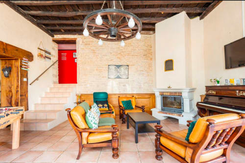 Rustikales Wohnzimmer der La Maison de la Colline in Vers, Frankreich mit Holzmöbeln, Kamin und Klavier