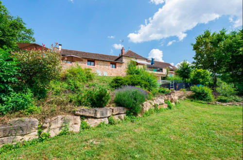 Steinhaus La Maison de la Colline in Vers, Frankreich mit üppigen Gärten und grünem Rasen unter blauem Himmel