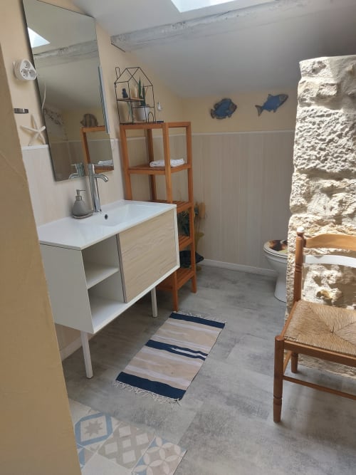 Modernes Badezimmer im Le Manoir Lacustre mit weißem Waschtisch, Holzregalen, Steinakzentwand und gestreiftem Badteppich