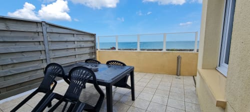 Seaside terrace at Relais des Iles cottage in Saint-Marcouf with table, chairs, and ocean view behind railing