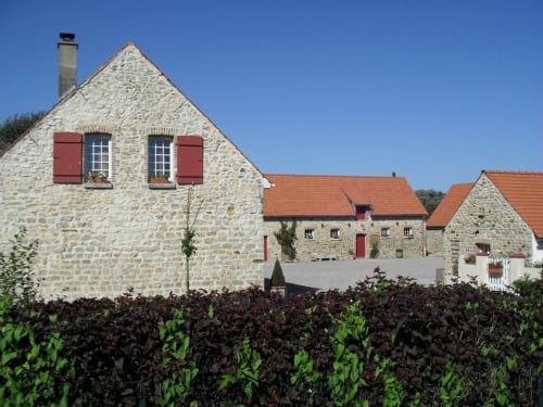 Domaine De La Ronville stone cottage with red shutters, terracotta roof, and manicured hedges in French countryside