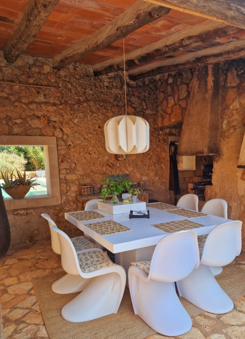 Salle à manger contemporaine à la villa Las Fincas De Annie avec chaises blanches, murs en pierre rustique, poutres apparentes et luminaire suspendu