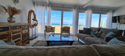 Bright coastal living room with sea views, modern furniture, wood dresser, and terrace access at Relais des Îles cottage,