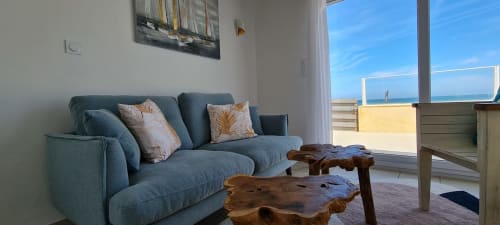 Coastal cottage living room with blue sofa, wooden coffee table, and sea view terrace at Relais des Îles, Saint-Marcouf