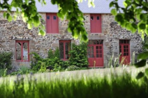 Stone farmhouse with red doors and windows at Domaine du Tertre Ychot in Dol de Bretagne, Brittany